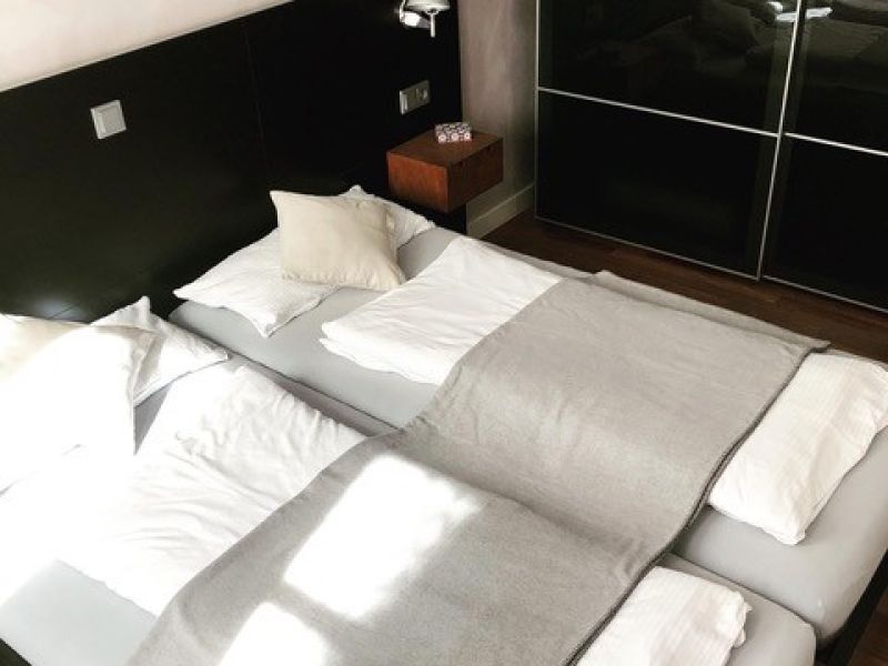 Detailaufnahme des zweiten Schlafzimmers mit komfortablem Doppelbett, hochwertiger Bettwäsche und großzügigem Kleiderschrank.